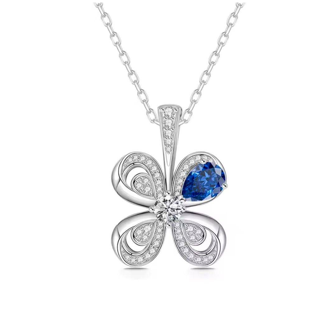 Silver flower-shaped pendant with a blue gemstone on a white background