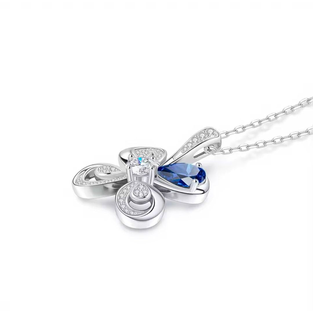 Silver butterfly pendant with a blue gemstone on a white background