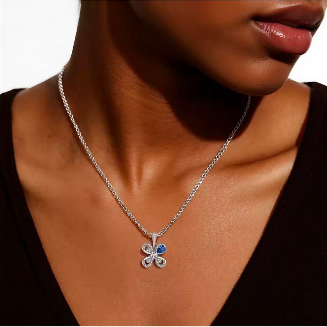 Silver necklace with a clover-shaped pendant worn by a person