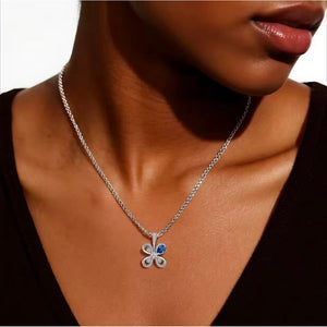 Silver necklace with a clover-shaped pendant worn by a person